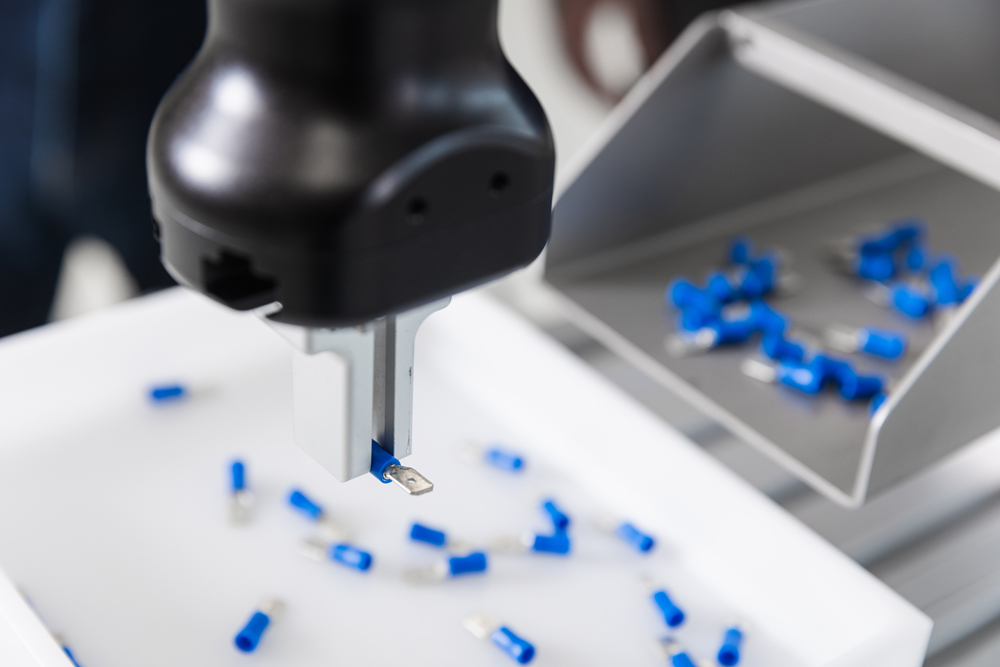 Préhenseur qui manipule une pièce électronique bleue